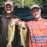 Two anglers holding up four bass
