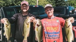 Two anglers holding up four bass