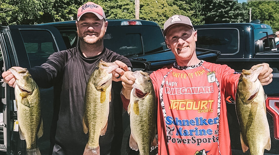 Two anglers holding up four bass
