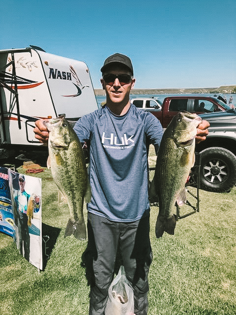 Kyle Gelles holding up two largemouth bass.