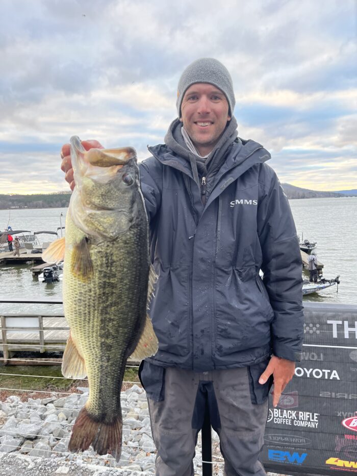 Kyle Gelles on a cold day holding up a largemouth bass after a tournament weigh in